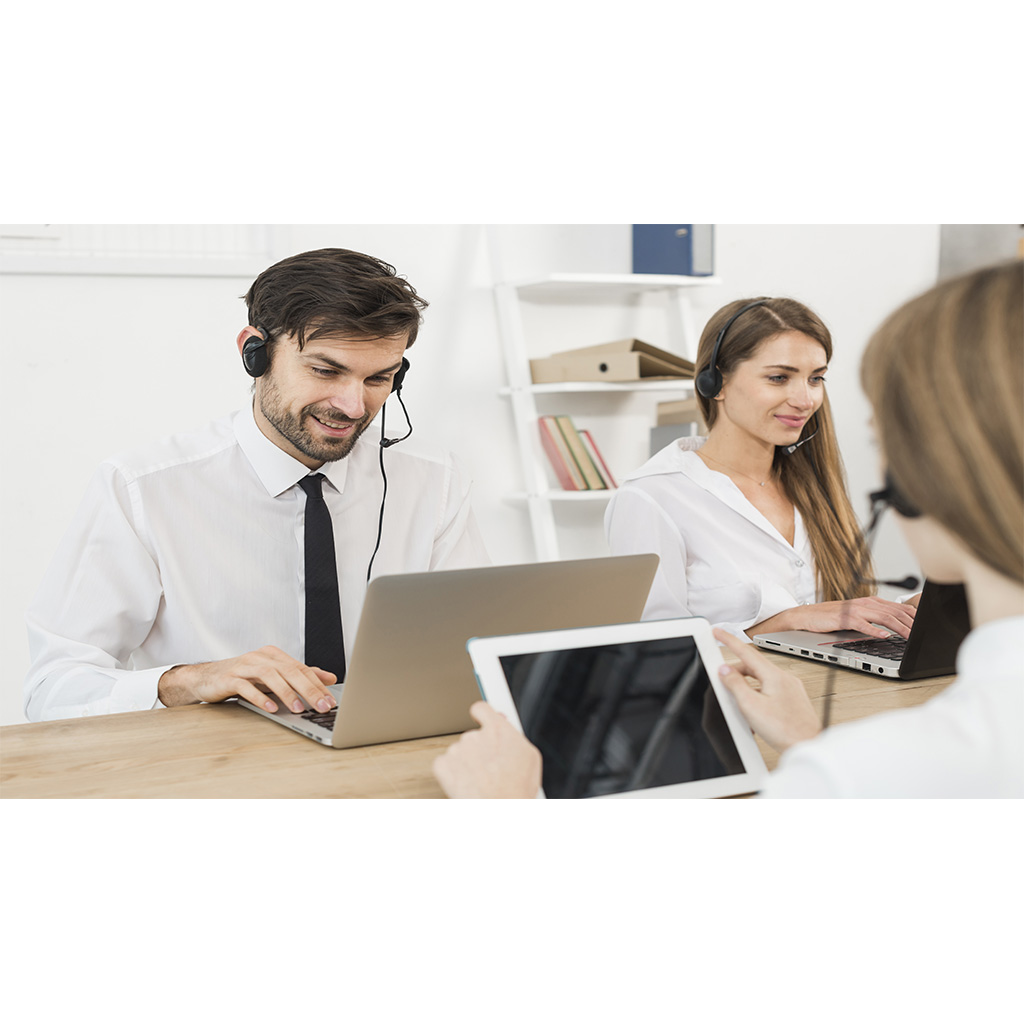 A woman conducting a mock interview with a man, both seated at a table with documents and a water bottle.
